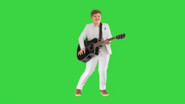 Beyazlı çocuk akustik gitar çalıyor ve yeşil ekranda dans ediyor, Chroma Key.