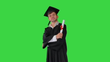 Mezuniyet elbisesi içinde gururlu bir erkek öğrenci yeşil ekranda diplomasıyla poz veriyor, Chroma Key..