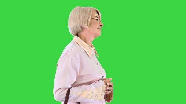 Intelligente senior vrouw in glazen lopen op een groen scherm, Chroma Key. — Stockvideo