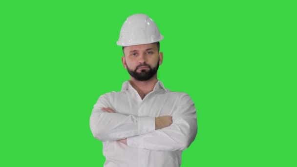 Упевнений інженер у білому шоломі стоїть і змінює пози, дивлячись на камеру на зеленому екрані, Chroma Key. — стокове відео