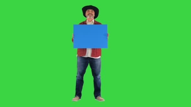 戴着帽子的老农在绿色屏幕上挂着空白标牌，铬钥匙. — 图库视频影像