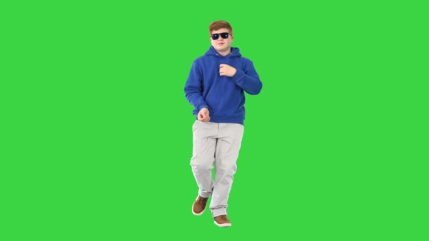 サングラスを歩くと緑の画面、クロマキーで踊るカジュアル男の子. — ストック動画