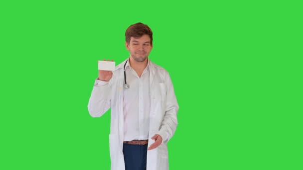 Médico masculino sorridente com estetoscópio andando e pílulas de publicidade em uma tela verde, Chroma Key. — Vídeo de Stock