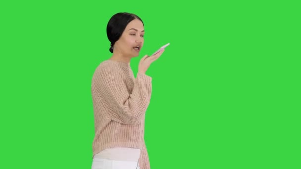 Mujer joven hablando por teléfono sosteniéndolo en su cara mientras camina en una pantalla verde, Chroma Key. — Vídeos de Stock