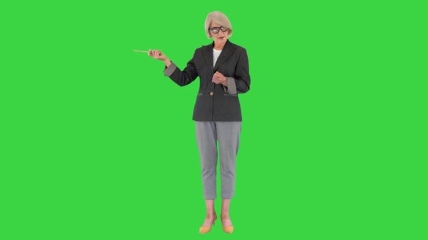 緑の画面で何かを説明し、指していると確信しているシニア女性教師,クロマキー. — ストック動画