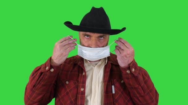 カウボーイは緑の画面、クロマキーのコロナウイルスを防ぐために医療用マスクを身に着けています. — ストック動画