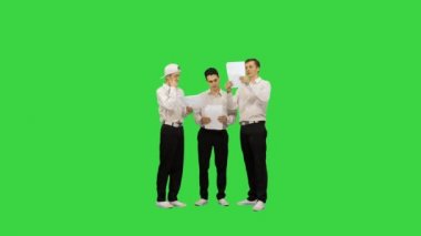 Benzer giyinmiş üç adam bir belgeyi okurken bir tanesi yeşil ekranda bacaklarını açıyor, Chroma Key..