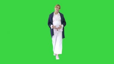 Yeşil ekranda yürüyen mutlu, hamile, sarışın bayan, Chroma Key.