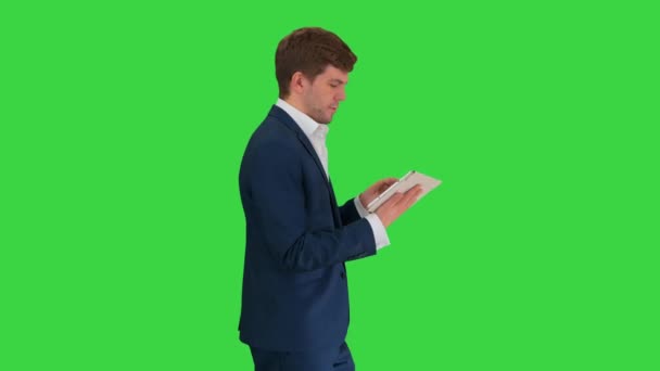 Hombre de negocios sonriente usando tableta digital mientras camina en una pantalla verde, Chroma Key. — Vídeos de Stock