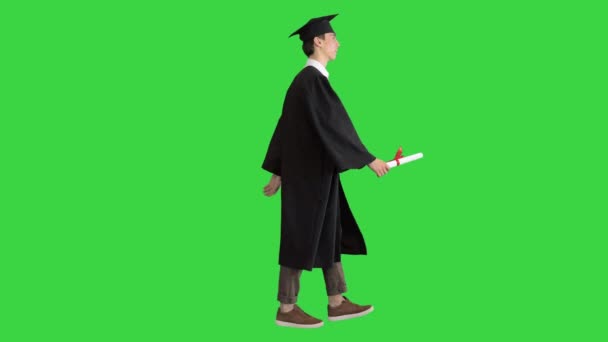 Absolvent student chůze a usmívá se na zelené obrazovce, Chroma Key.