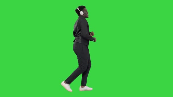 男は音楽を聞いて、緑の画面、クロマキーを歩いている間に踊る. — ストック動画