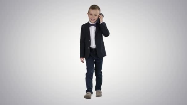 Niño pequeño en un disfraz haciendo una llamada telefónica mientras camina sobre fondo degradado. — Vídeos de Stock