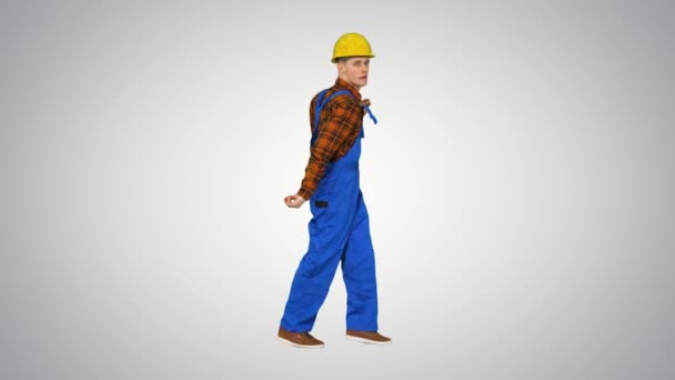 Dancing young engineer with helmet after work on gradient background. — Stock Video