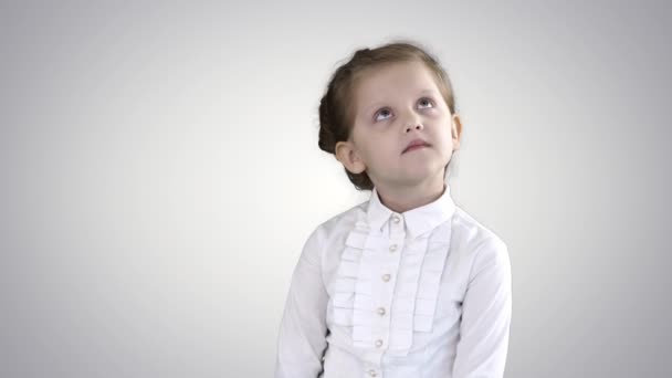 Mignonne préscolaire fille debout être timide regarder autour et penser sur dégradé fond. — Video