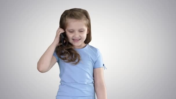 Liten söt flicka gör ett telefonsamtal när du går på lutning bakgrund. — Stockvideo