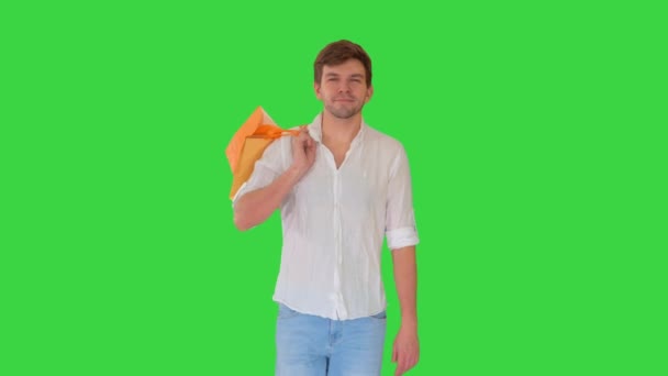 Homem bonito em roupas casuais andando com sacos de compras olhando para a câmera em uma tela verde, Chroma Key. — Vídeo de Stock