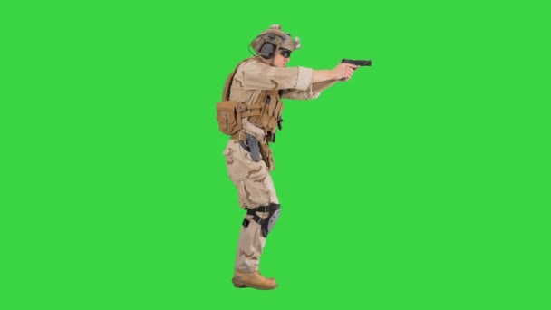 Gewapende soldaat in camouflage loopt en richt met een pistool op een groen scherm, Chroma Key. — Stockvideo