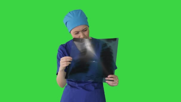 Denkende vrouwelijke arts in uniform onderzoeken van een borst röntgenfoto op een groen scherm, Chroma Key. — Stockvideo