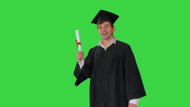 Estudante do sexo masculino feliz em roupão de graduação renúncia com seu diploma em uma tela verde, Chroma Key. — Vídeo de Stock