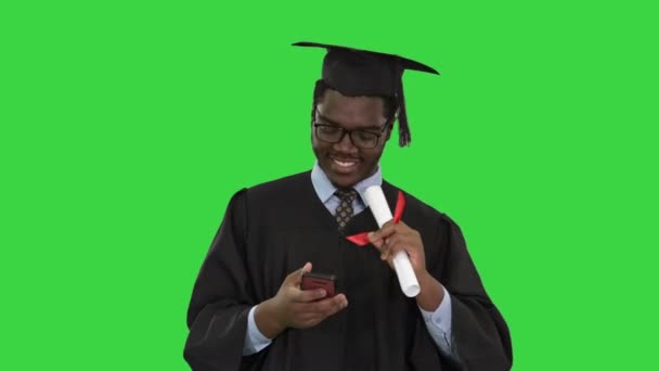 Šťastný africký americký muž student v absolventském županu, přičemž telefon selfies s diplomem na zelené obrazovce, Chroma Key. — Stock video