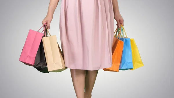 Dopo la giornata di shopping Giovane donna che trasporta borse della spesa mentre cammina su sfondo gradiente. — Foto Stock