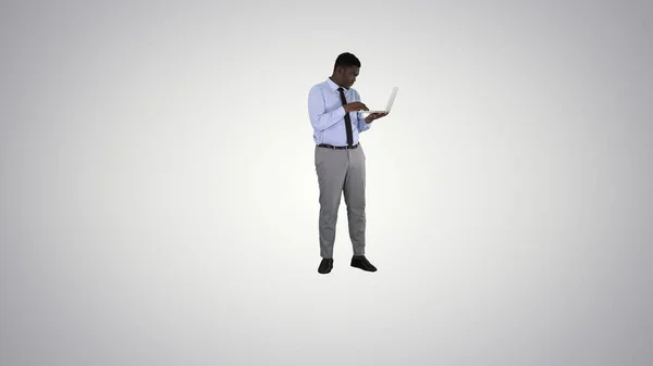 Hombre de negocios afroamericano que trabaja con computadora portátil en el fondo de gradiente. — Foto de Stock