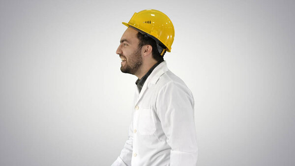 Smiling construction engineer catching a cap and putting it on on gradient background.