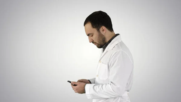 Zbliżenie portret przystojnego pracownika służby zdrowia lub lekarza lub pielęgniarki, SMS-y na telefon komórkowy na tle gradientu. — Zdjęcie stockowe