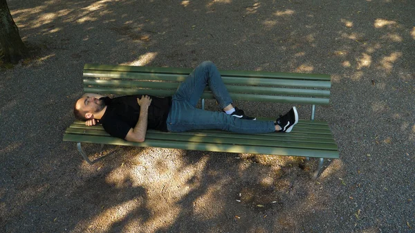 Män sover på en bänk i parken. — Stockfoto