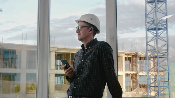 Stavební dělník poslouchá hudbu ze svého telefonu s drátem — Stock fotografie