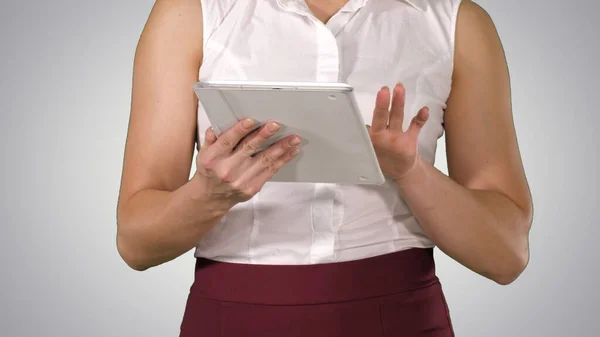 Femme tenant tablette numérique et l'utilisant tout en marchant sur fond de dégradé. — Photo