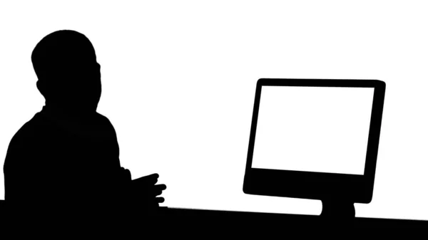 Silhouette Casual Geschäftsmann lächelt und spricht in die Kamera zeigt etwas auf dem Monitor des Computers. — Stockfoto