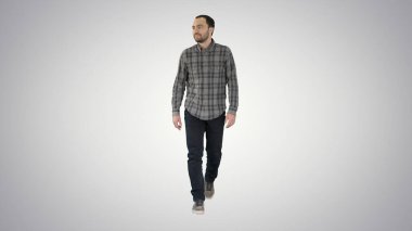 Kot pantolon ve gömlek giymiş rahat bir adam. Arkaplanda yürüyor ve yan tarafa bakıyor..