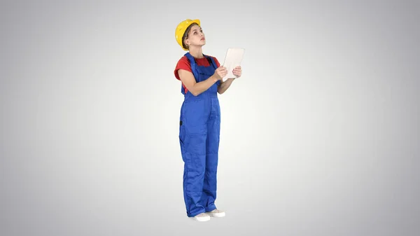 Sarı kasklı kadın mühendis, gradyan arka plandaki inşaat binasını kontrol ederken tablet bilgisayar arıyor.. — Stok fotoğraf