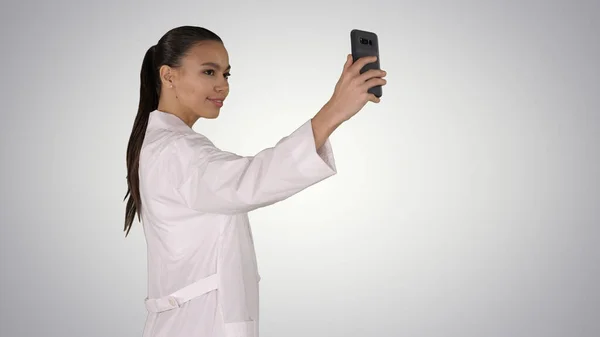 Stilvolle europäische Doktor Brünette, die Selfie auf dem Handy macht, während sie auf dem Gefällehintergrund geht. — Stockfoto