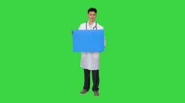 Gülümseyen erkek doktor steteskop takıyor ve yeşil ekranda boş bir poster tutuyor, Chroma Key.