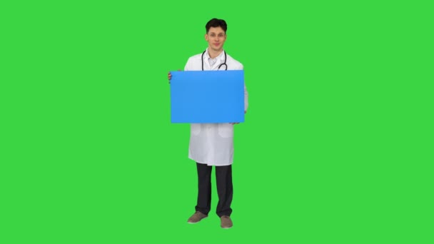 Gülümseyen erkek doktor steteskop takıyor ve yeşil ekranda boş bir poster tutuyor, Chroma Key. — Stok video