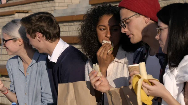 Šťastný tisíciletý přátelé jíst sendviče venku. — Stock fotografie