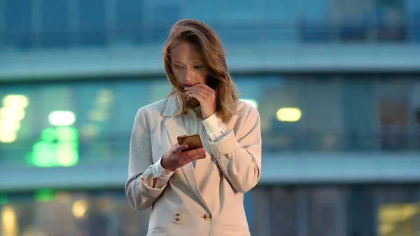 Mulher de negócios olhando para o telefone celular na cidade à noite. — Fotografia de Stock