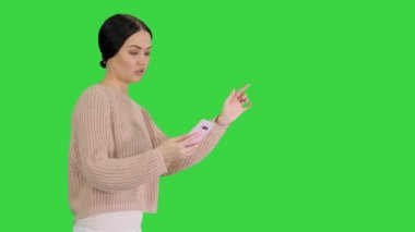 Yeşil Ekran 'da yürürken selfie çeken sıradan kıyafetlerle gülümseyen güzel bir kadın, Chroma Key.