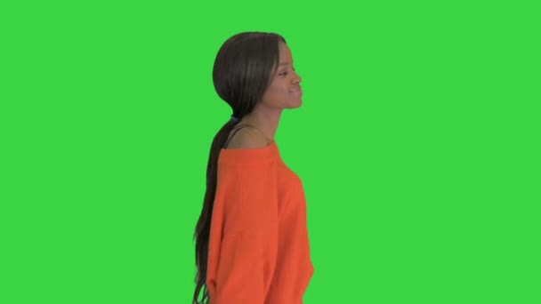 Розслаблена афріканська молода жінка, одягнена в яскравий випадковий одяг танцюючи під час прогулянки на зеленому екрані, Chroma Key. — стокове відео
