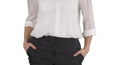 Beyaz arka planda elleri cebinde yürüyen rahat iş kadını..