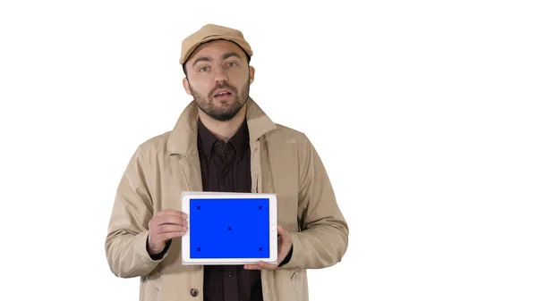 Hombre en trinchera caminando y sosteniendo la tableta con pantalla azul maqueta presentando algo sobre fondo blanco. —  Fotos de Stock