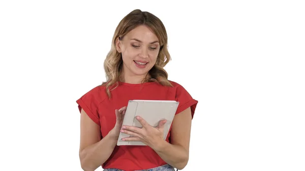 Blonde woman in red holding tablet and reading to camera from it on white background. — Stock Photo, Image