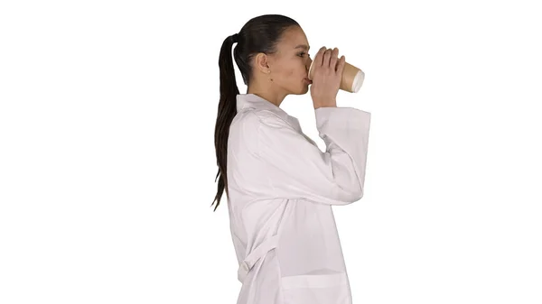 Vrouwelijke arts drinken van koffie en wandelen op witte achtergrond. — Stockfoto