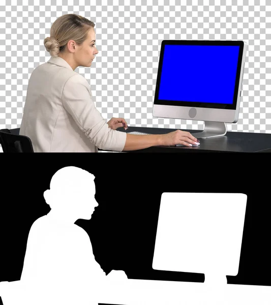 Een jonge vrouw aan het werk, aan het bureau, kijkend naar de monitor, Alpha Channel. Blauw scherm Mock-up Display. — Stockfoto