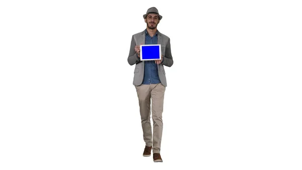 Случайный человек в шляпе ходьба и показ цифровой планшет в камеру на белом фоне. — стоковое фото