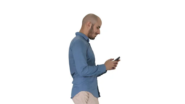 Молодий чоловік ходить і використовує телефон на білому тлі . — стокове фото