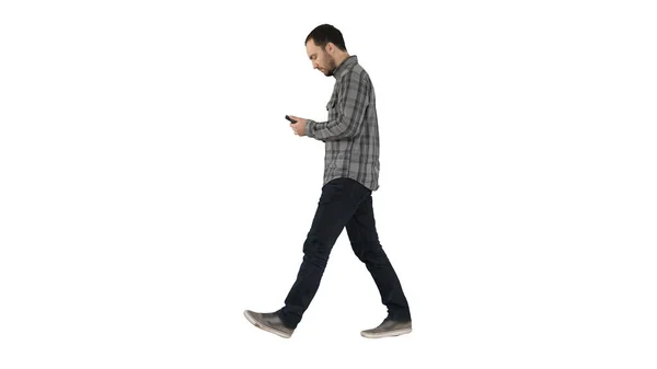 Молодой умный случайный человек ходит и читает сообщение на мобильном телефоне на белом фоне. — стоковое фото