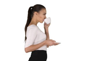 Beyaz fincanlı güzel esmer kadın çay ya da kahve ile beyaz arka planda yürüyor..